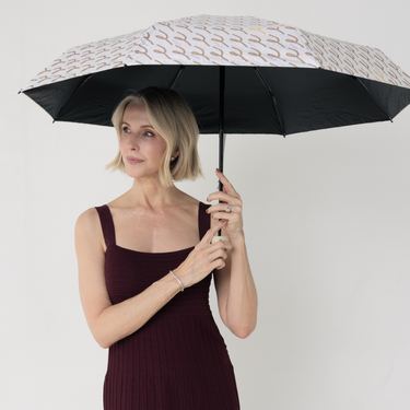 Woman holding UPF50+ sun umbrella. black on the inside, brand print on the outside.